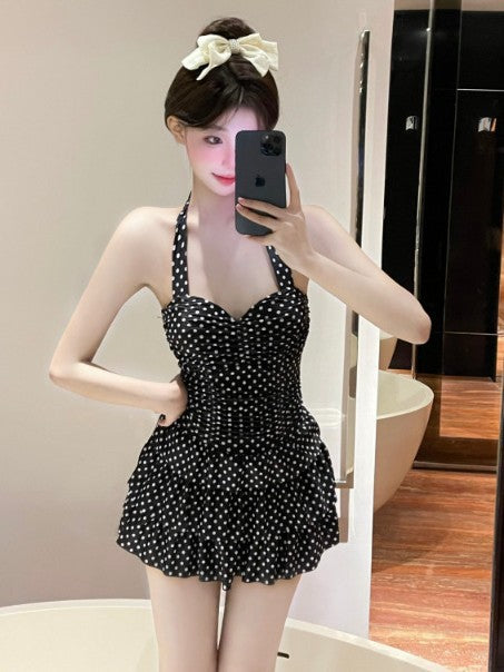 Woman taking a mirror selfie wearing a black polka dot dress.