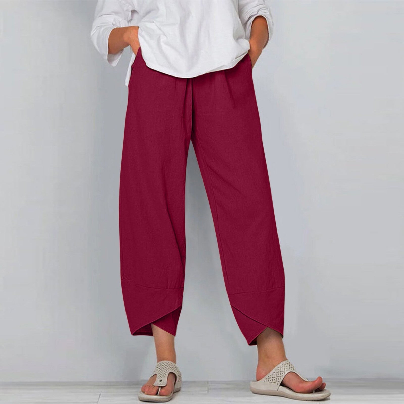 Person wearing maroon wide-leg pants and a white top against a plain background