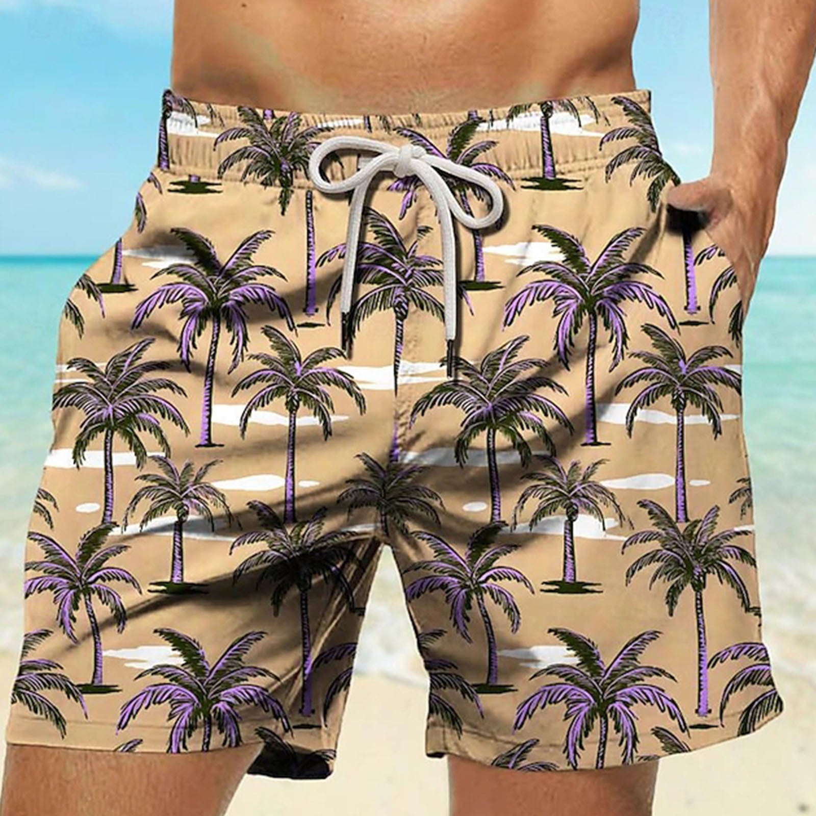 Beige shorts with palm tree pattern worn by a person against a beach background