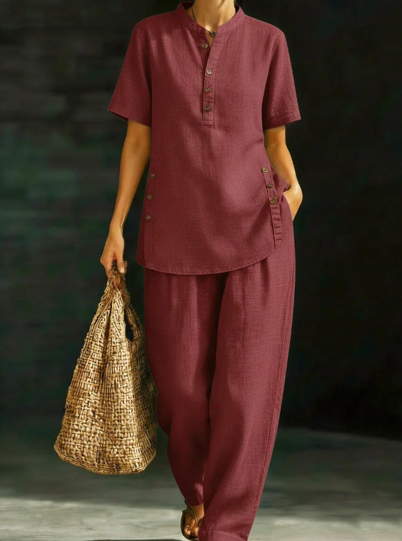 Person wearing a maroon outfit holding a woven bag against a dark background
