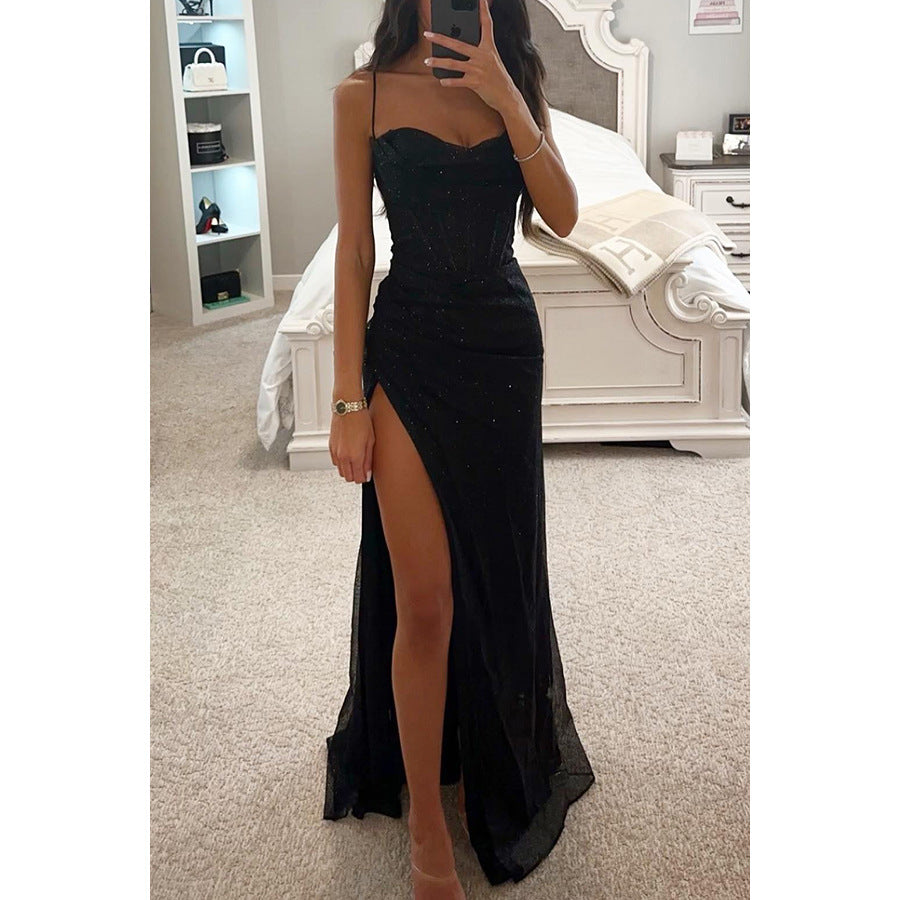 Person wearing a black dress with a high slit in a bedroom setting