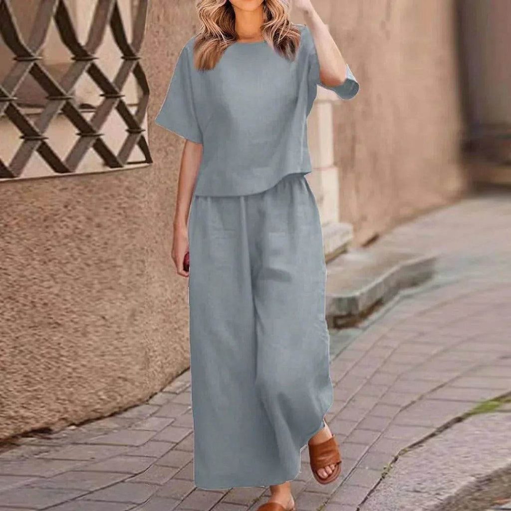 Woman in stylish light blue two-piece outfit and sandals walking on a cobblestone street, ZA-Zola fashion