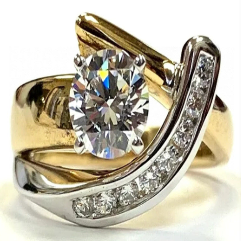 Gold and silver ring with a large diamond and smaller diamonds on the band against a white background