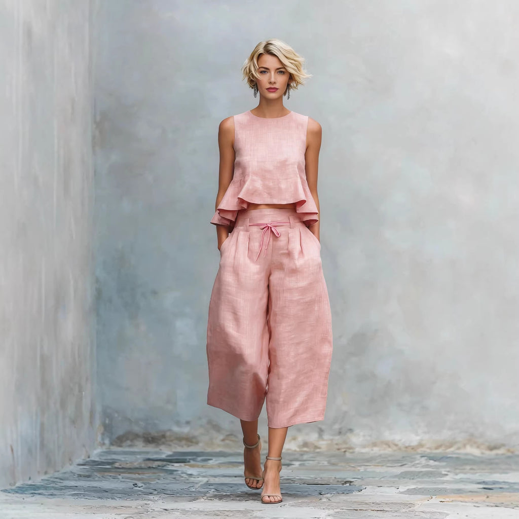 Woman wearing a pink outfit against a textured gray wall.
