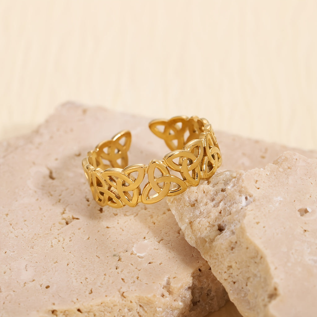 Gold Celtic knot ring on a beige stone surface