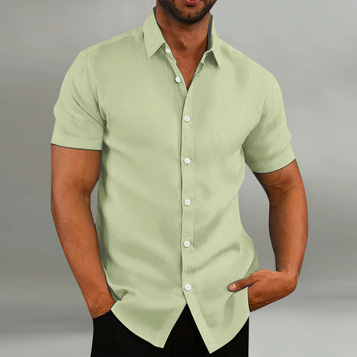 Man wearing a light green short-sleeve shirt against a gray background