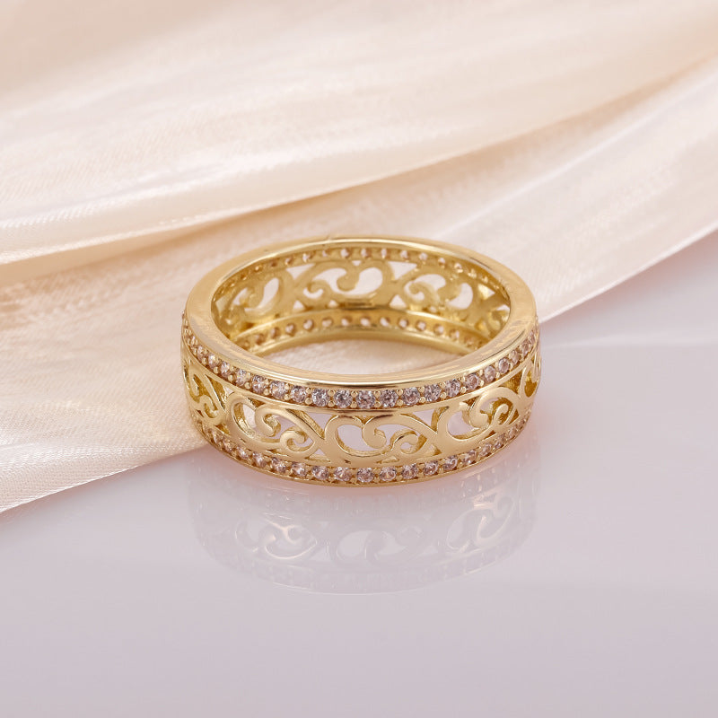Gold ring with intricate design on a soft fabric background