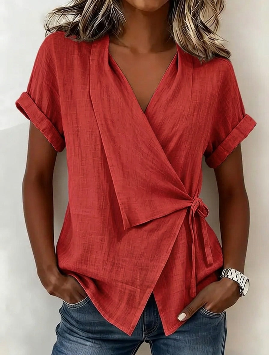 Person wearing a red wrap top with rolled-up sleeves against a neutral background