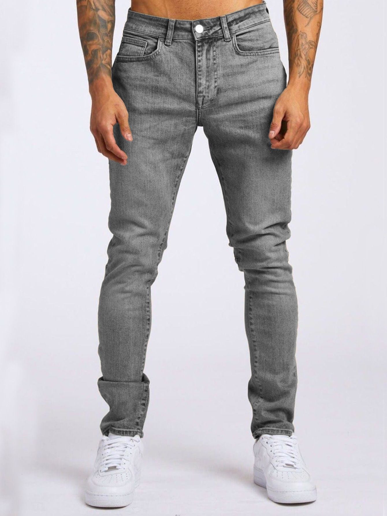 Person wearing gray jeans and white sneakers on a white background