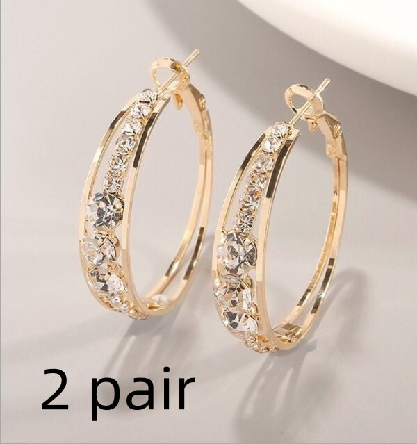 Gold hoop earrings with clear stones on a light gray background