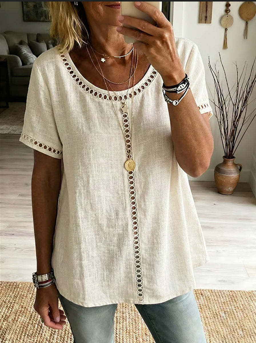 Woman wearing a beige blouse with intricate details in a home setting