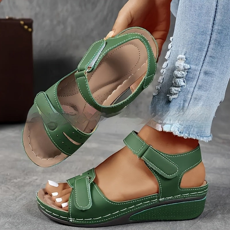 Green sandals worn with light blue jeans on a neutral background