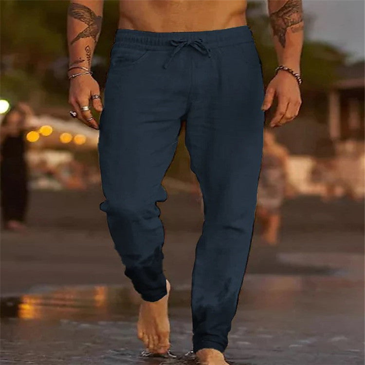 Person wearing navy blue jogger pants walking on a beach with a blurred background