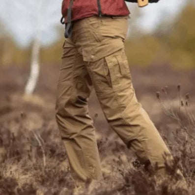 Person wearing tan cargo pants and a red jacket in a natural setting