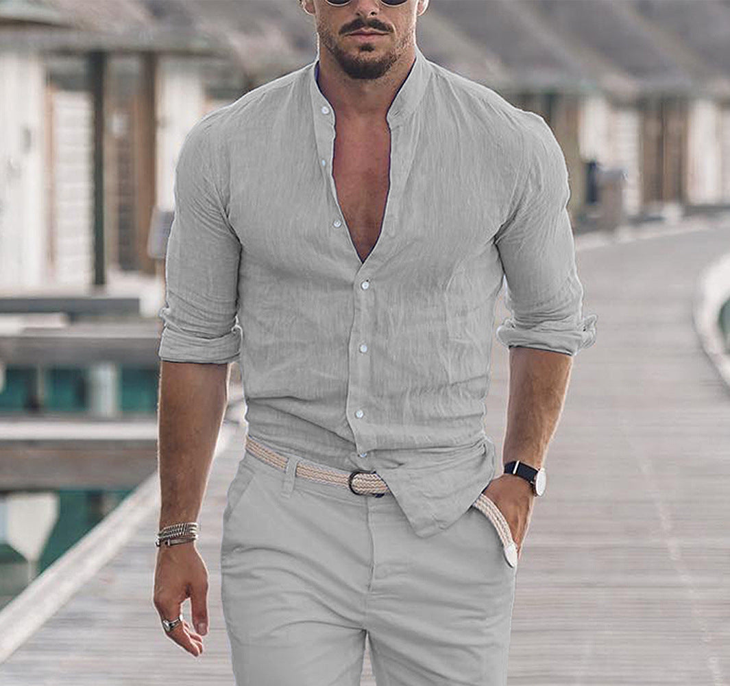 Man wearing a light gray shirt and pants on a wooden deck.