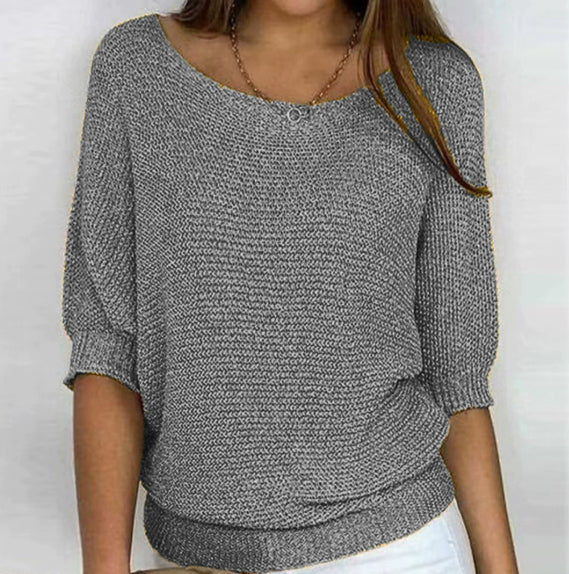 Person wearing a gray knitted sweater on a white background