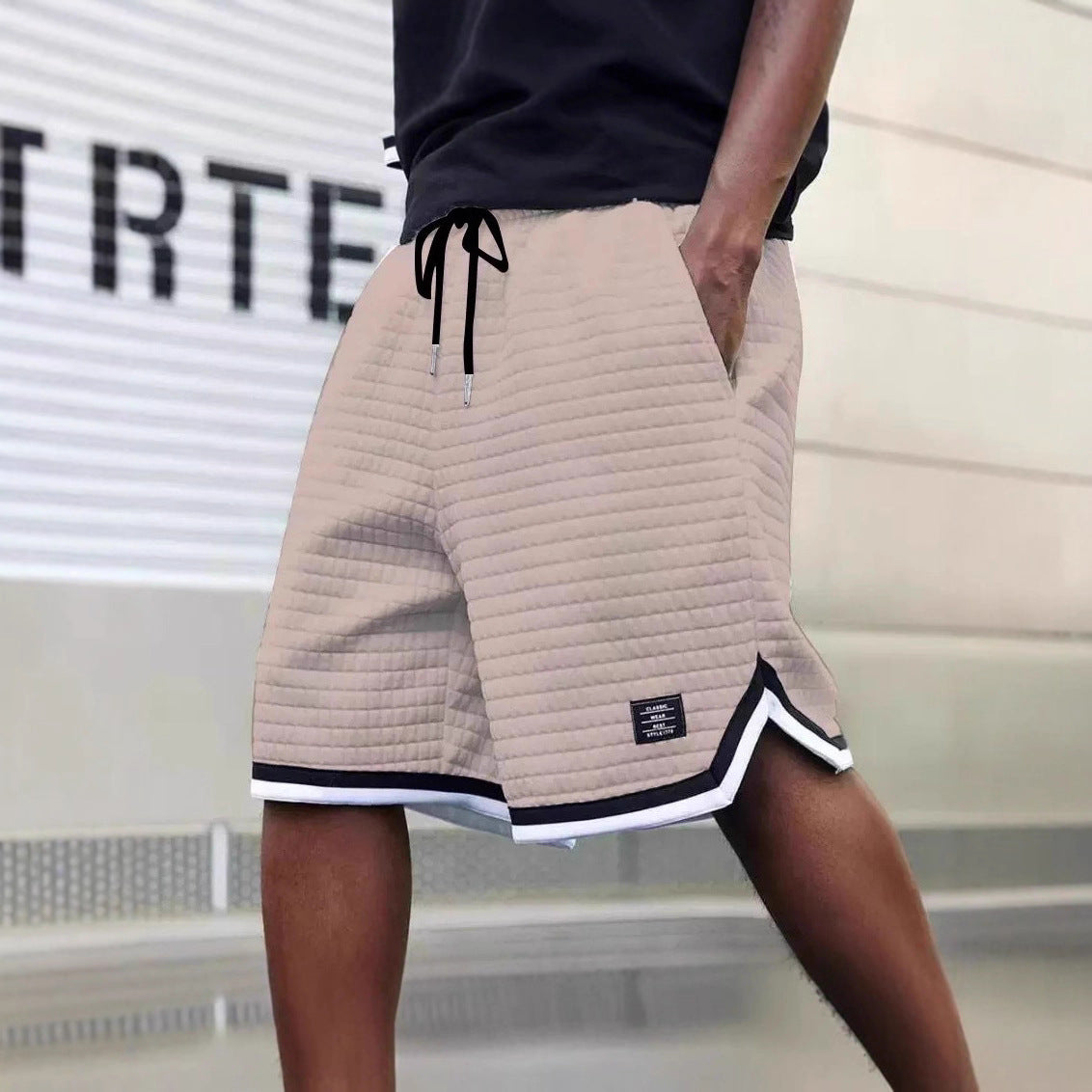 Beige shorts with black drawstring and white trim worn by a person, with a blurred background.