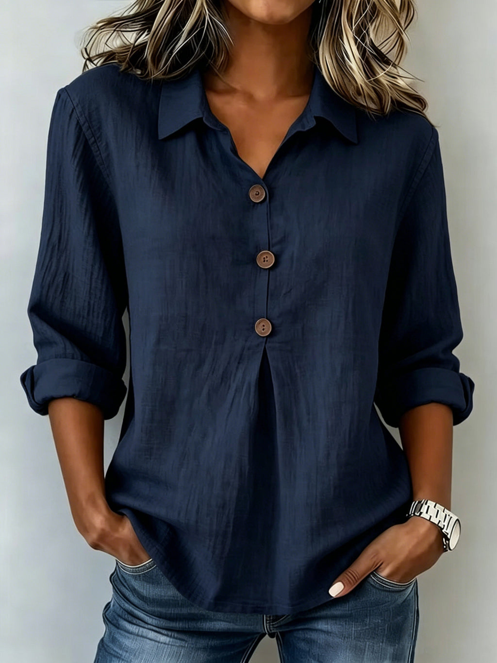Person wearing a navy blue button-up shirt with rolled-up sleeves against a plain background