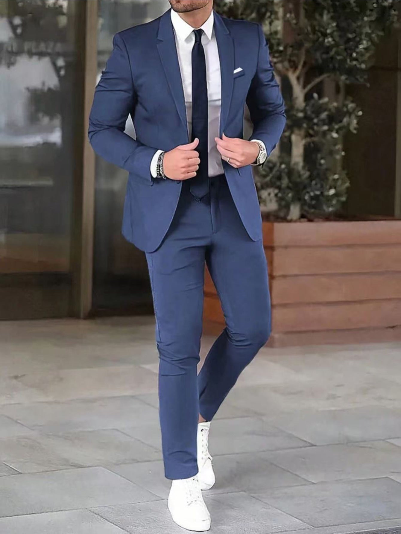 Man wearing a blue suit with white shoes on a city street.