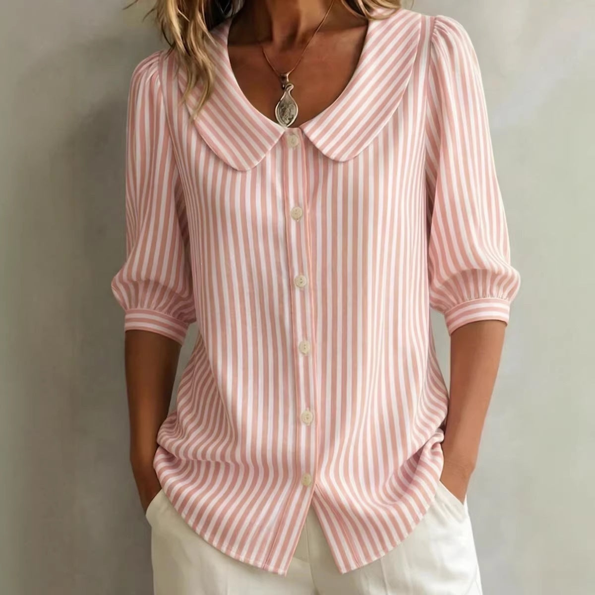 Pink and white striped shirt worn by a person against a neutral background