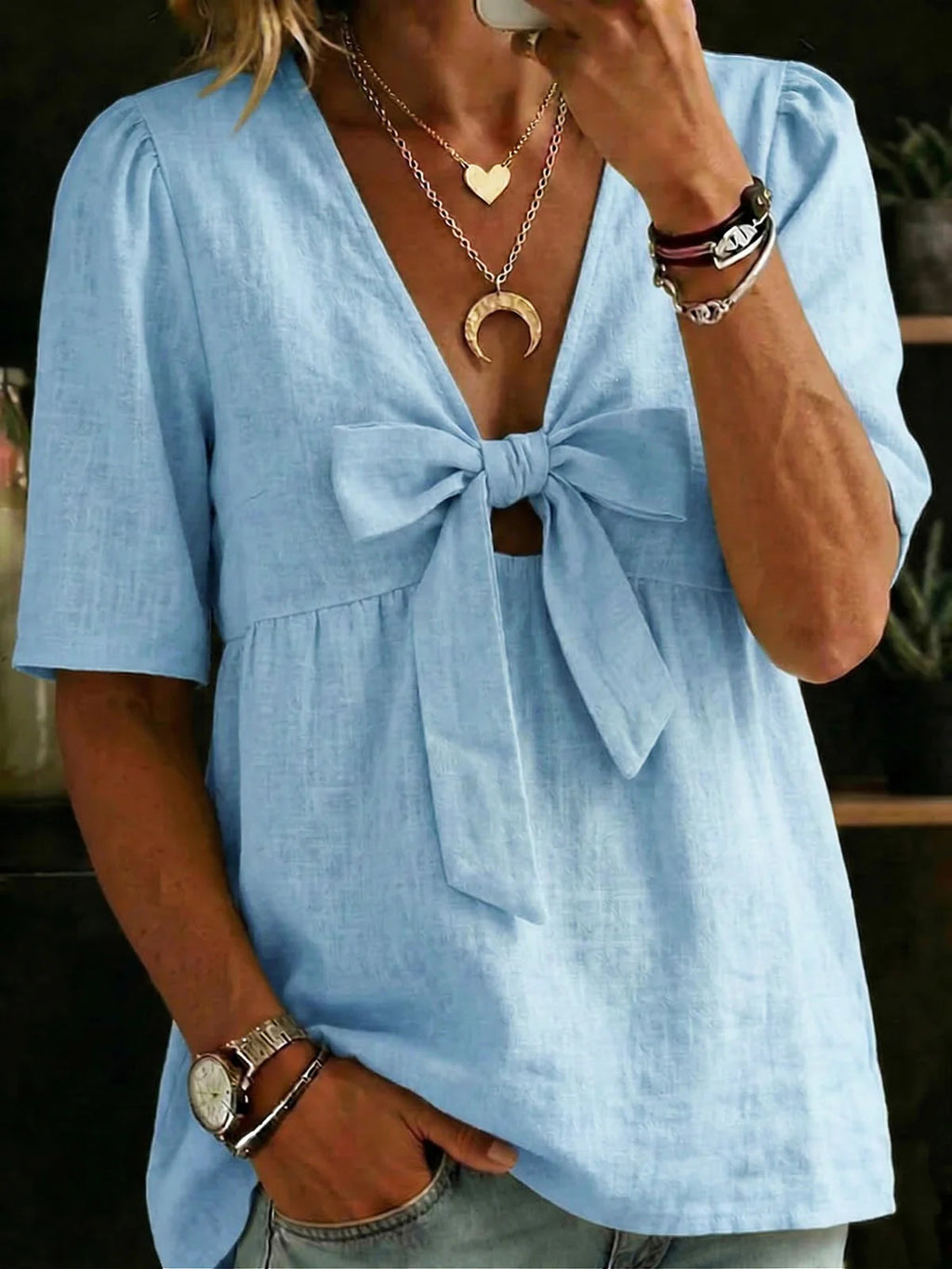 Light blue blouse with a bow detail worn by a person, with jewelry visible.