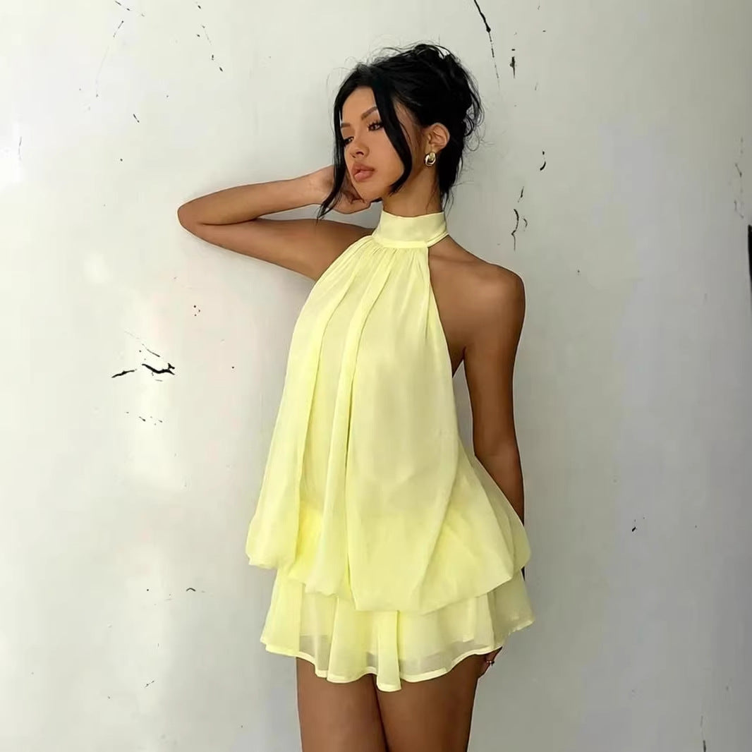 Woman wearing a light yellow halter neck dress against a white background