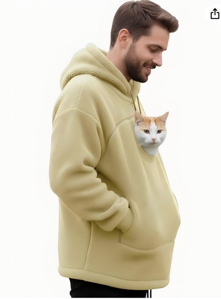 A man wearing a pale yellow sherpa fleece hoodie with a cat pocket containing a white and orange cat, shown against a plain white background.