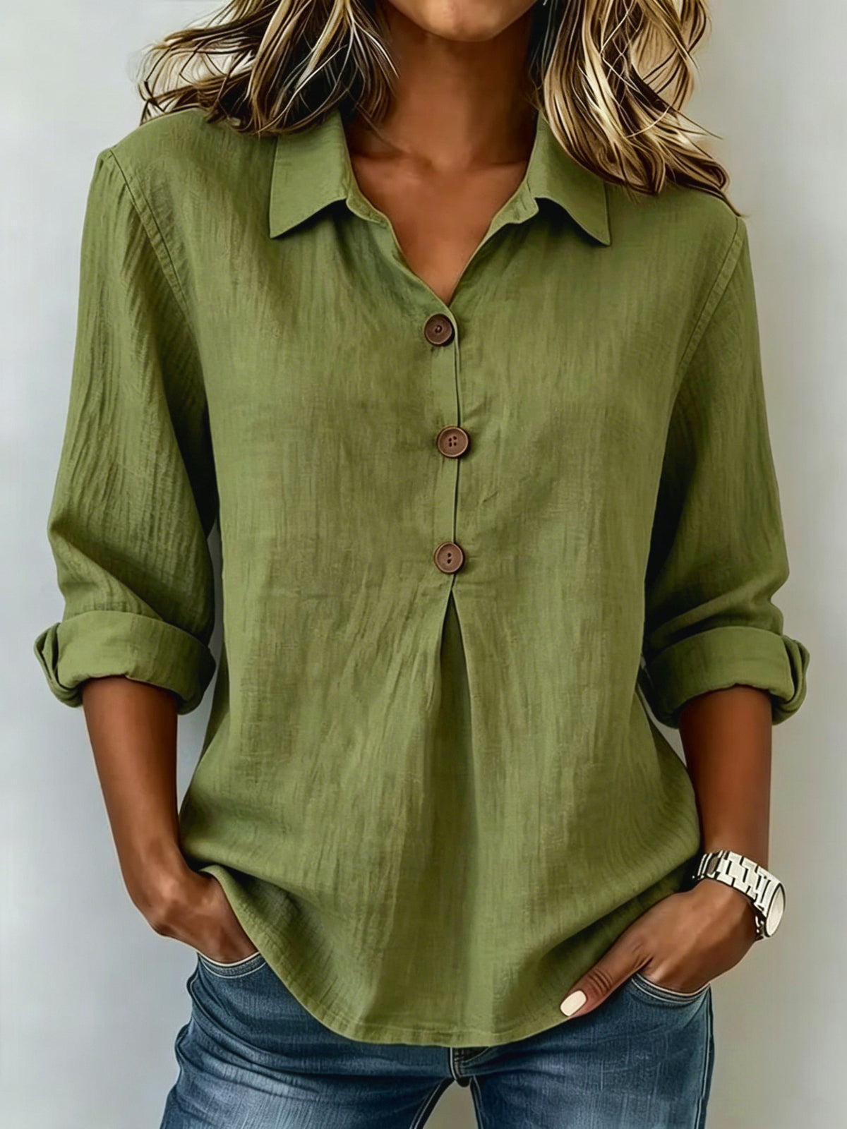 Person wearing a green button-up shirt with rolled-up sleeves against a plain background