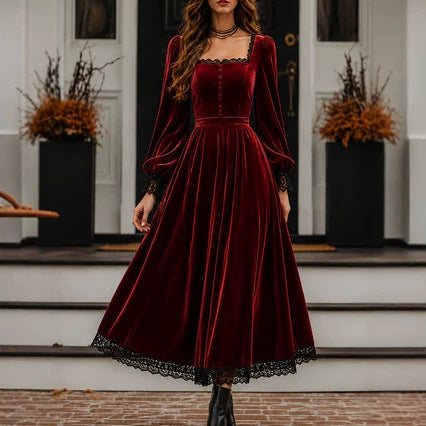 Woman wearing a burgundy velvet dress with black lace trim in front of a house.