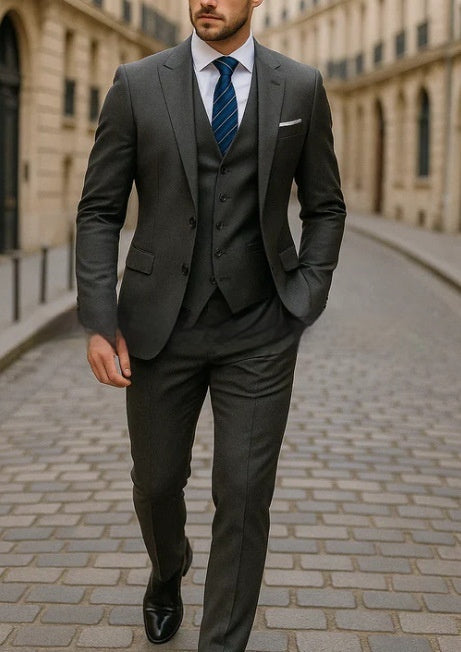 Man in a gray suit walking on a cobblestone street.