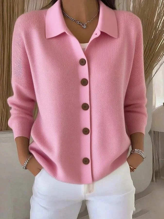 Person wearing a pink cardigan with brown buttons in an indoor setting