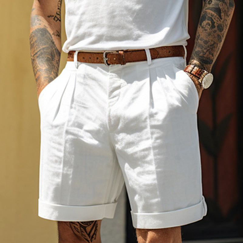 Person wearing white shorts and a white shirt with tattoos on arms, holding a bottle.