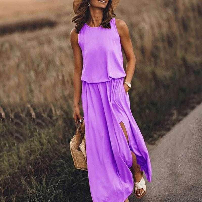Woman in a sleeveless purple maxi dress with side slit, straw hat, and woven bag outdoors