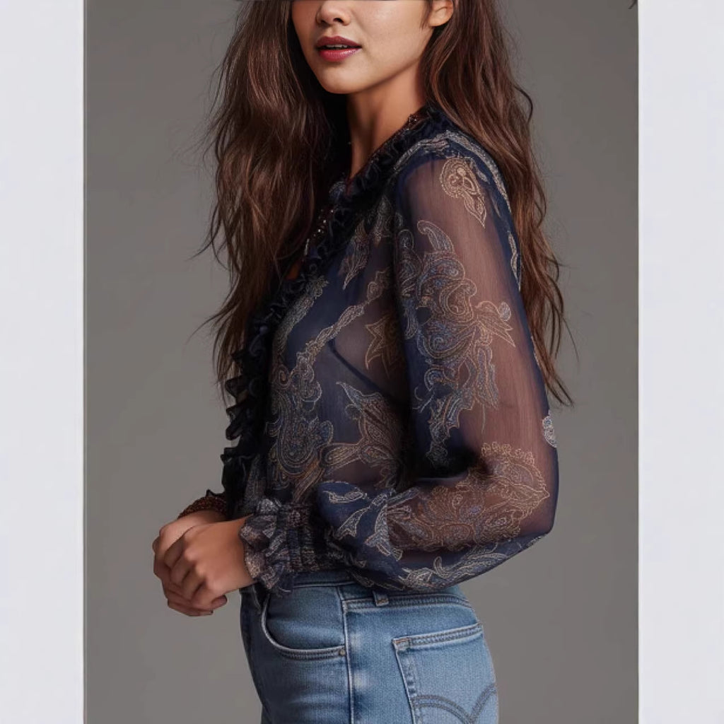 Woman wearing a sheer blouse with lace details and blue jeans against a gray background