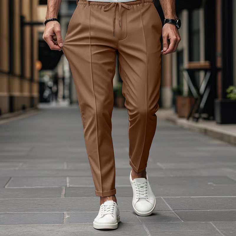 Person wearing brown pants and white sneakers on a city street.