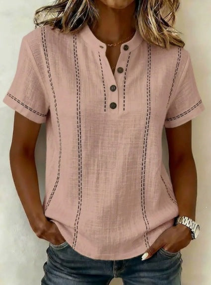 Person wearing a pink short-sleeve shirt with button details on a plain background