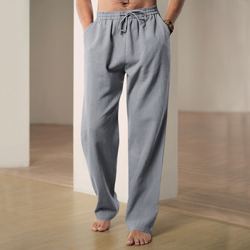 Person wearing light blue pajama pants standing in a minimalistic room.
