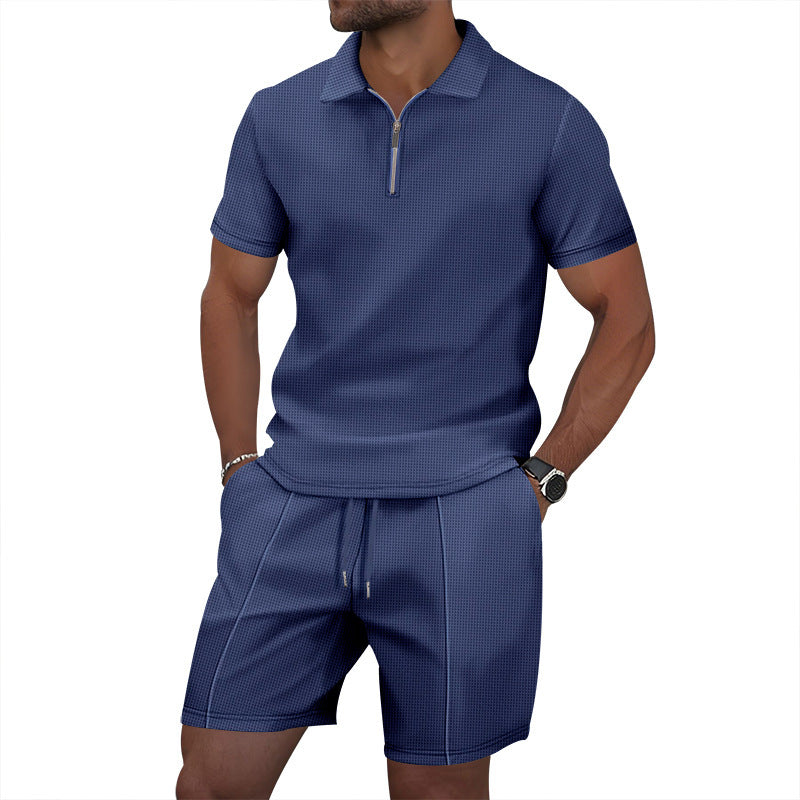 Man wearing a blue textured polo shirt and shorts set on a white background