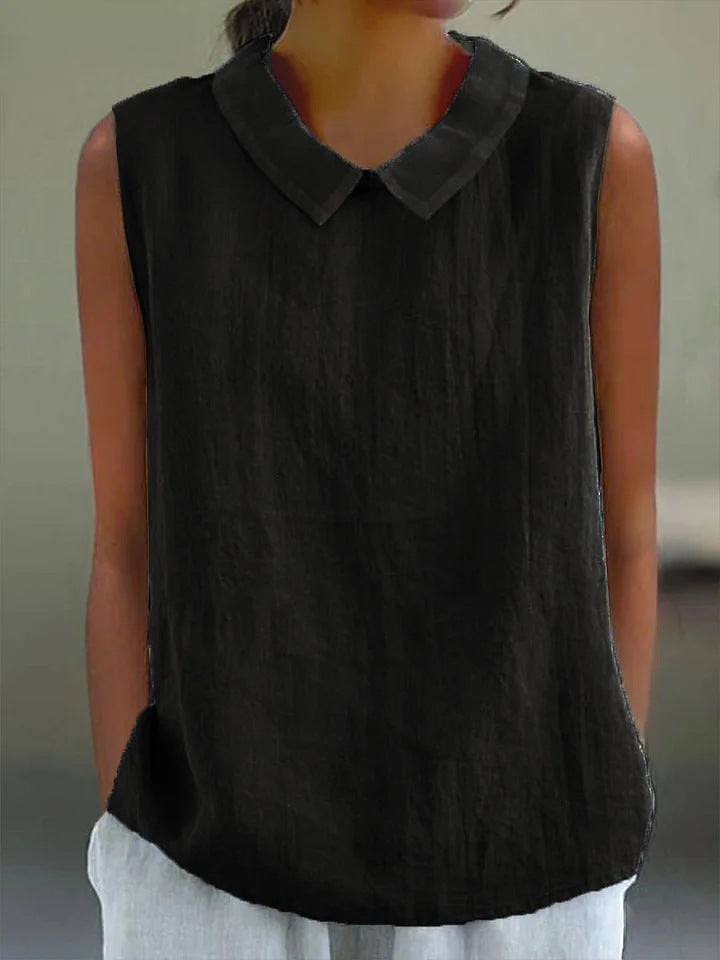 Dark sleeveless top with a collar worn by a person against a neutral background