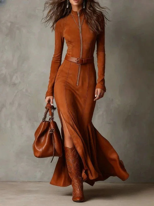 Woman wearing a brown dress and boots holding a matching handbag against a neutral background