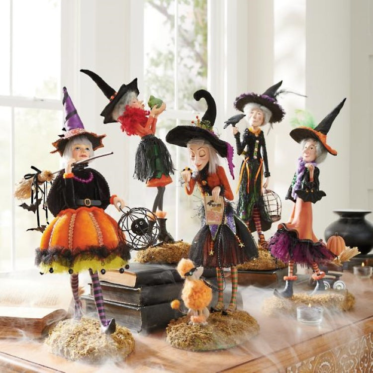 Set of Halloween-themed witch figurines on a decorative surface with a window in the background.