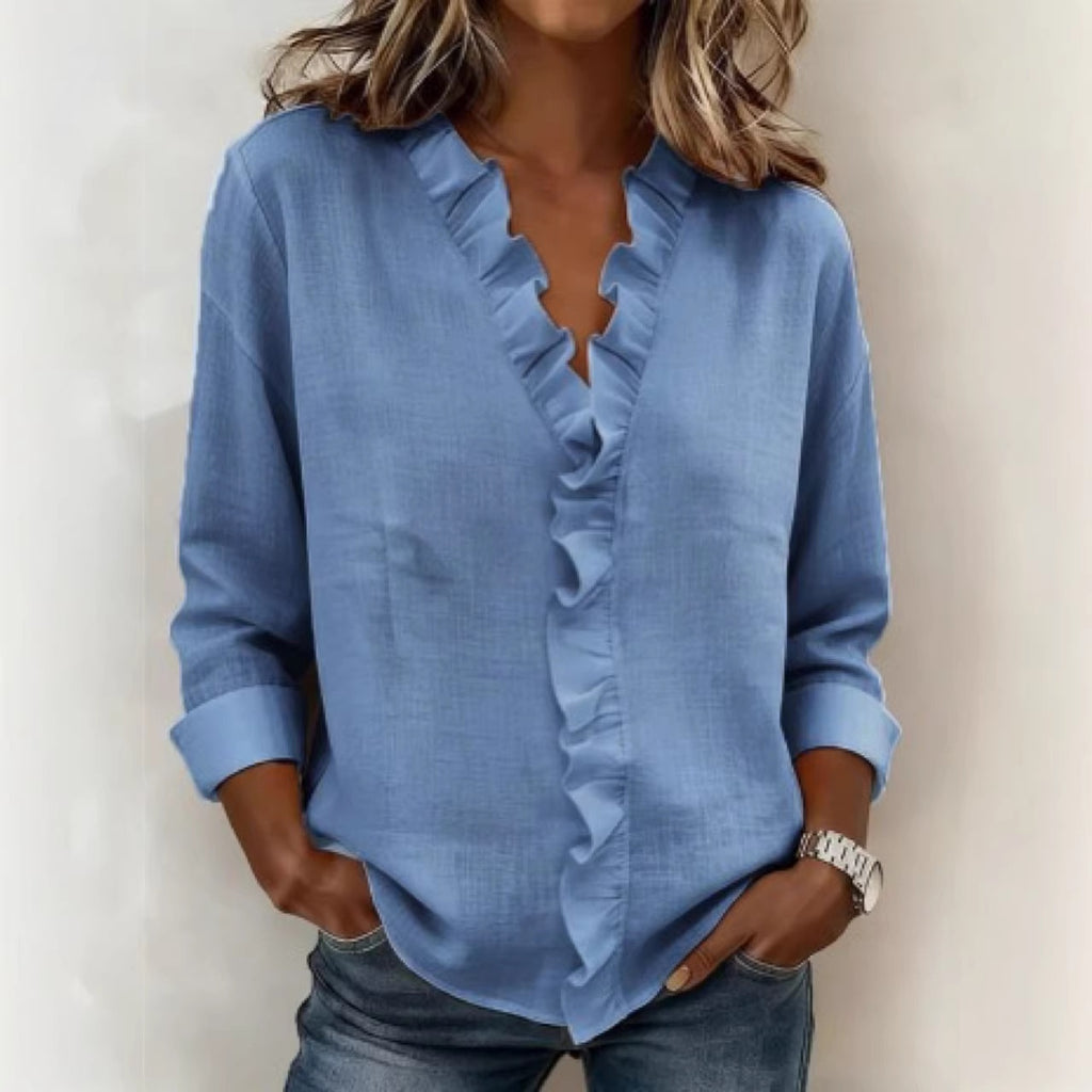 Woman wearing a blue ruffled blouse against a plain background