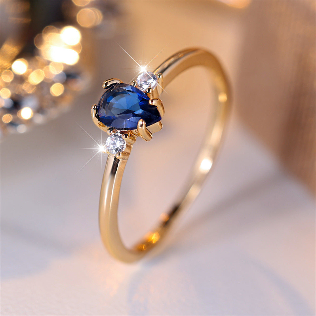 Gold ring with a blue gemstone and diamonds on a soft background