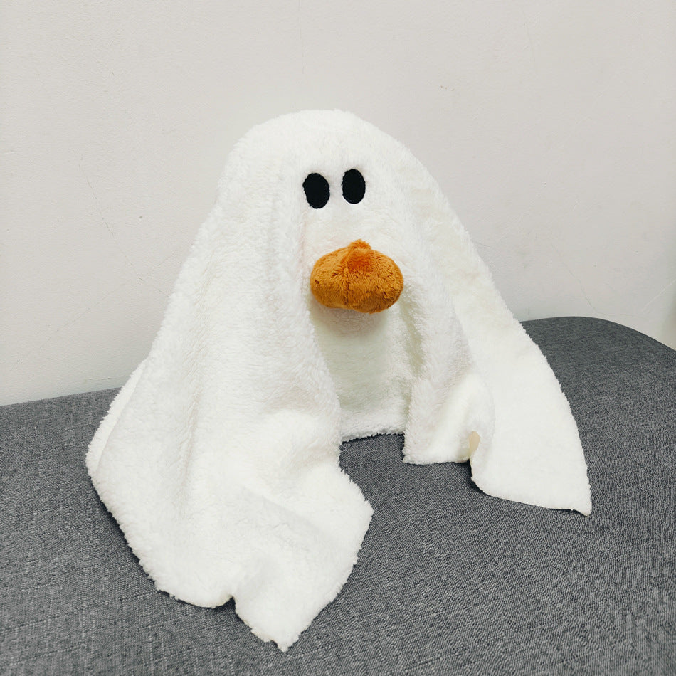 White ghost plush toy with black eyes and orange nose on a gray surface.