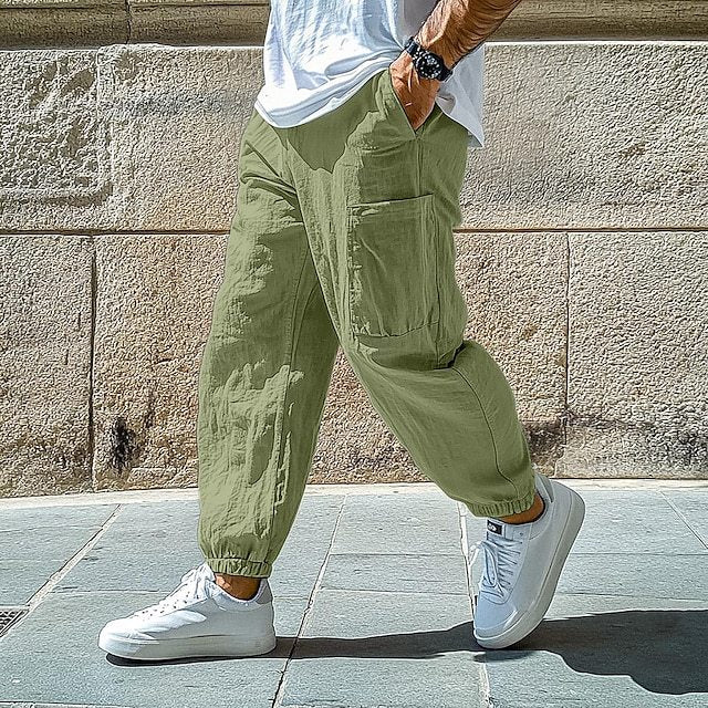 Person wearing green cargo pants and white sneakers against a stone wall.