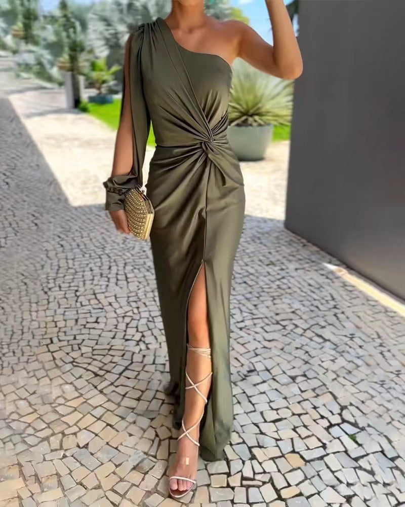 Woman wearing a green one-shoulder dress with a slit on a stone pavement.