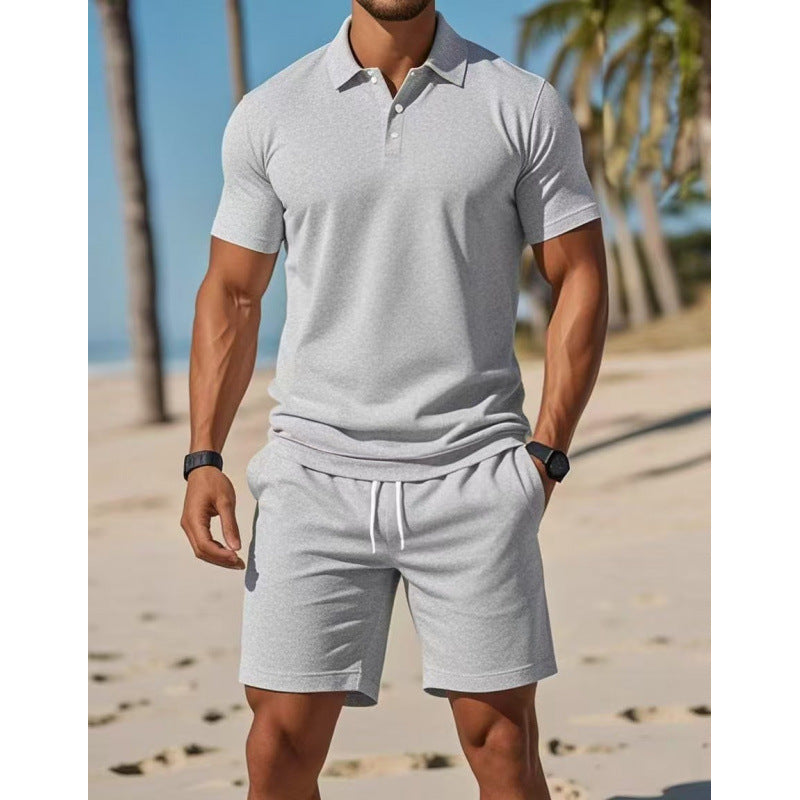 Man wearing a gray polo shirt and shorts on a beach