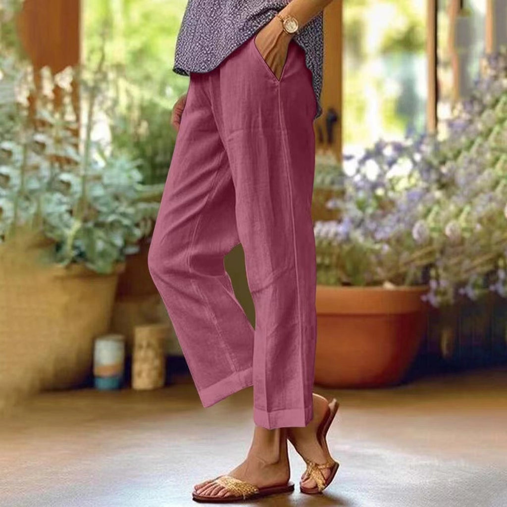 Person wearing pink pants standing in a garden with plants and flowers in the background