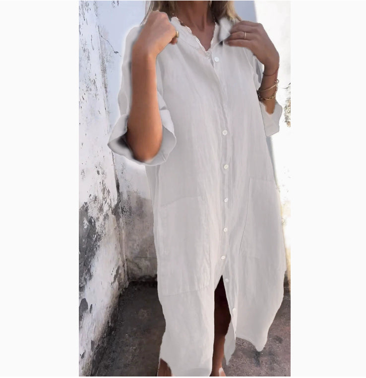 White button-up shirt worn by a person against a white wall.