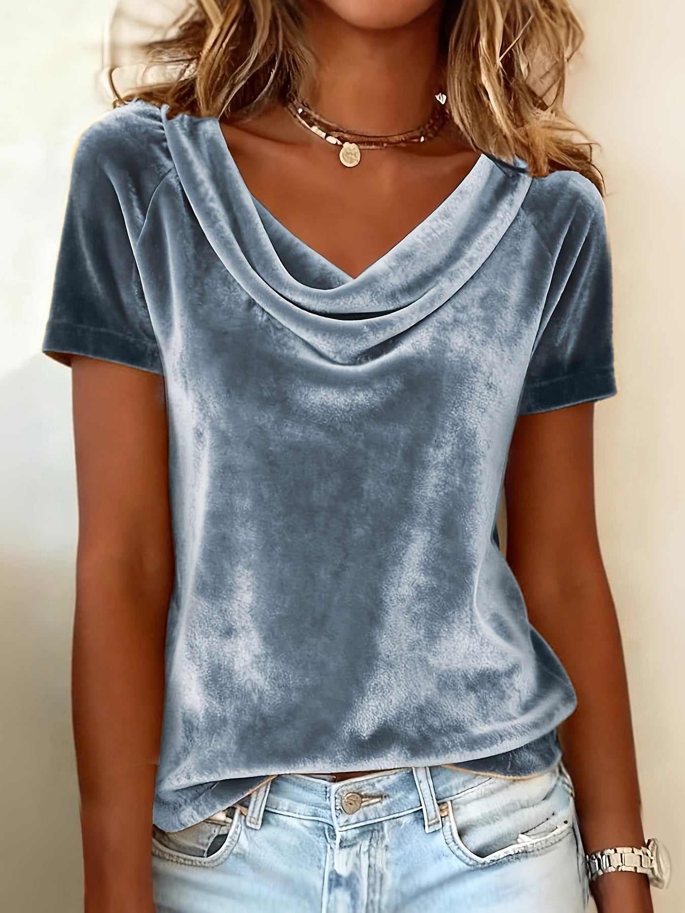 Person wearing a blue velvet top and denim shorts against a neutral background